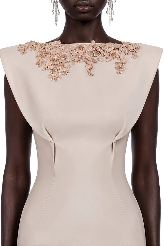 A close-up of a model wearing a beige bodycon dress with a wide boat neckline adorned with 3D floral applique in a matching beige tone.