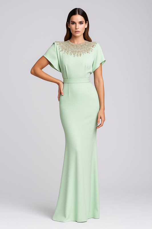 Woman wearing a light green evening gown with cap sleeves and beaded neckline on a gray background