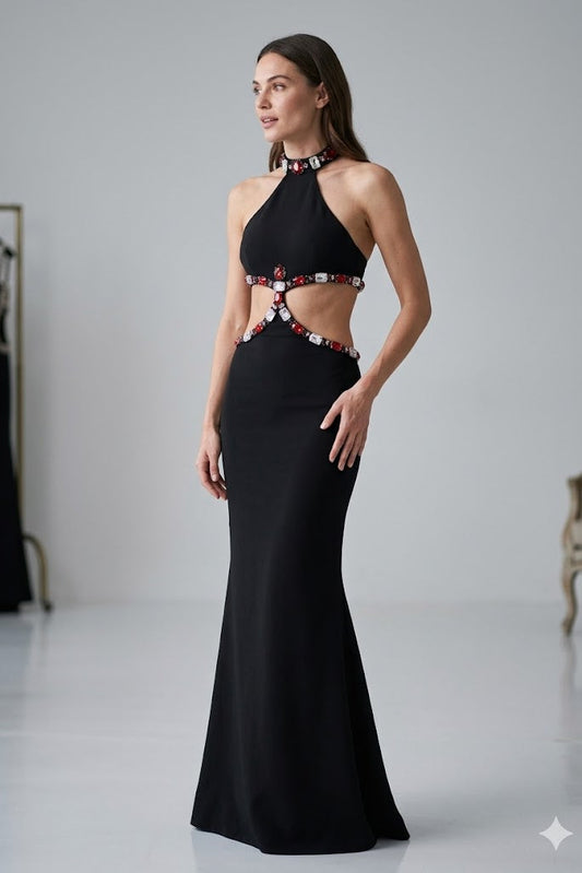Woman wearing a black evening gown with red embellishments in a studio setting