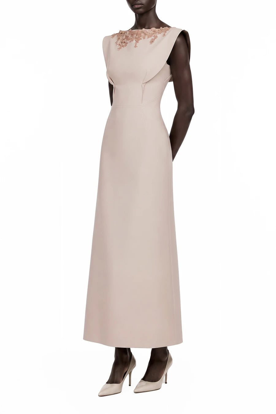 A sleeveless floor-length gown in a pale blush pink or nude tone, featuring a structured peplum-style waist and delicate floral lace applique across the upper chest, shown on a dark mannequin against a plain white background.
