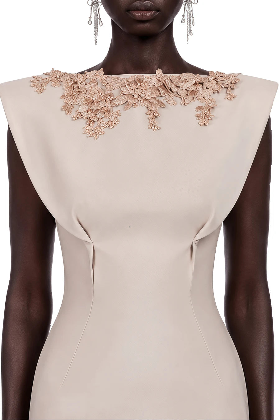 A close-up of a model wearing a beige bodycon dress with a wide boat neckline adorned with 3D floral applique in a matching beige tone.