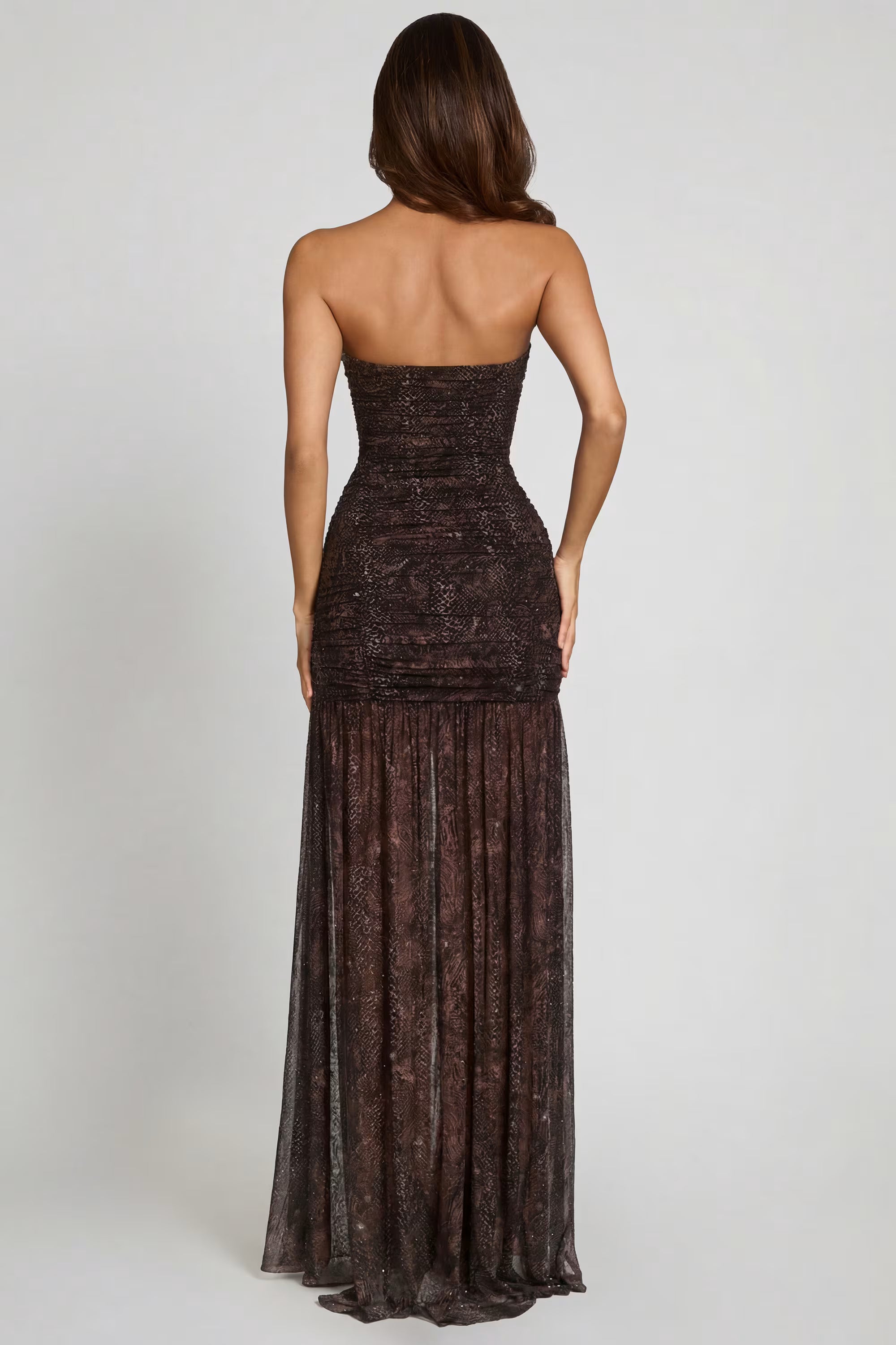 Woman wearing a strapless, long, dark brown dress on a white background