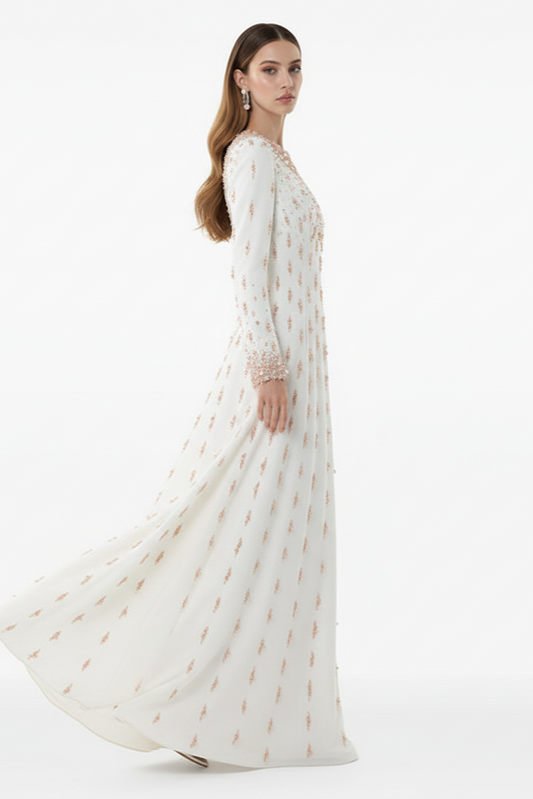 Woman wearing a long white dress with gold patterns on a white background