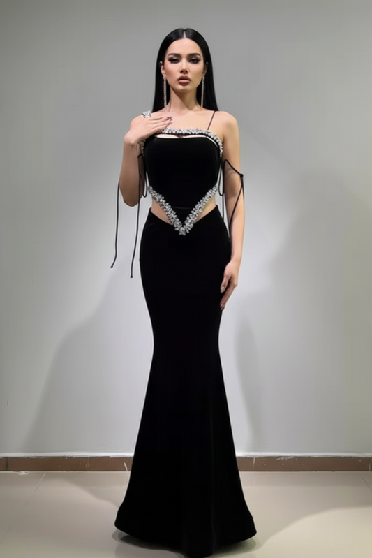 Woman wearing a black evening gown with cut-out design against a plain background