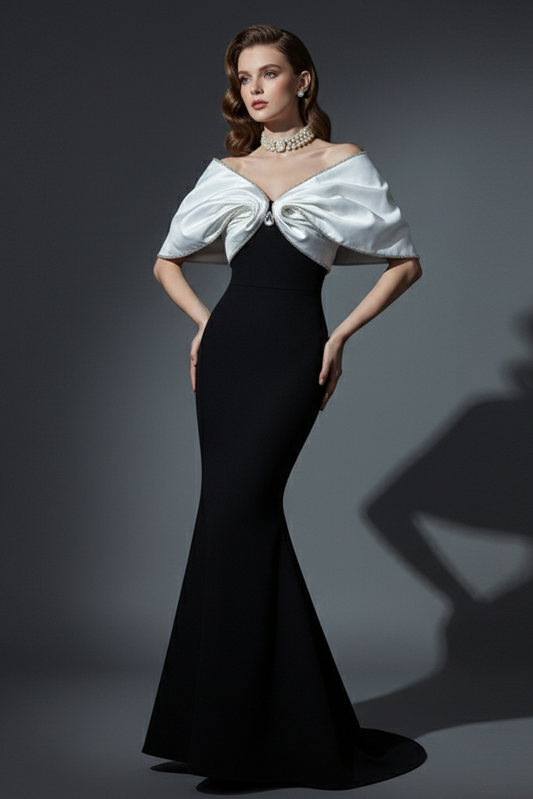Woman wearing a black evening gown with a white bow detail on a gray background
