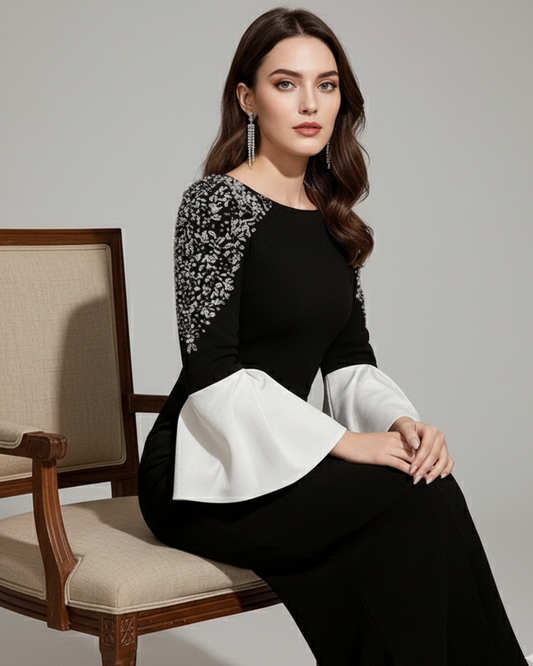Woman wearing a black and white dress sitting on a chair against a gray background