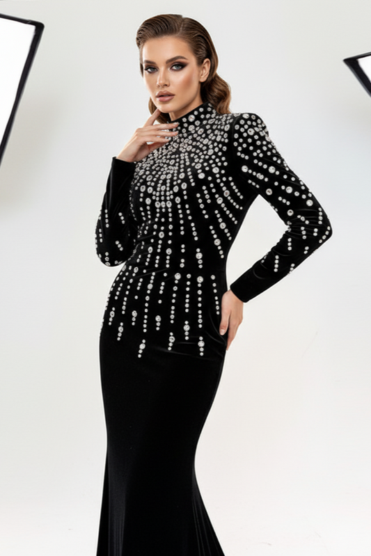 Woman wearing a black evening gown with silver embellishments against a white background