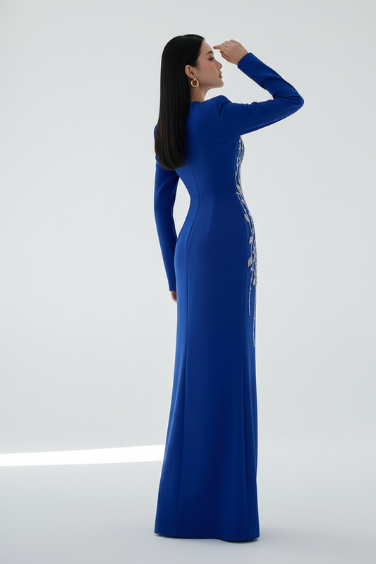 Woman wearing a blue evening gown with intricate detailing on a white background