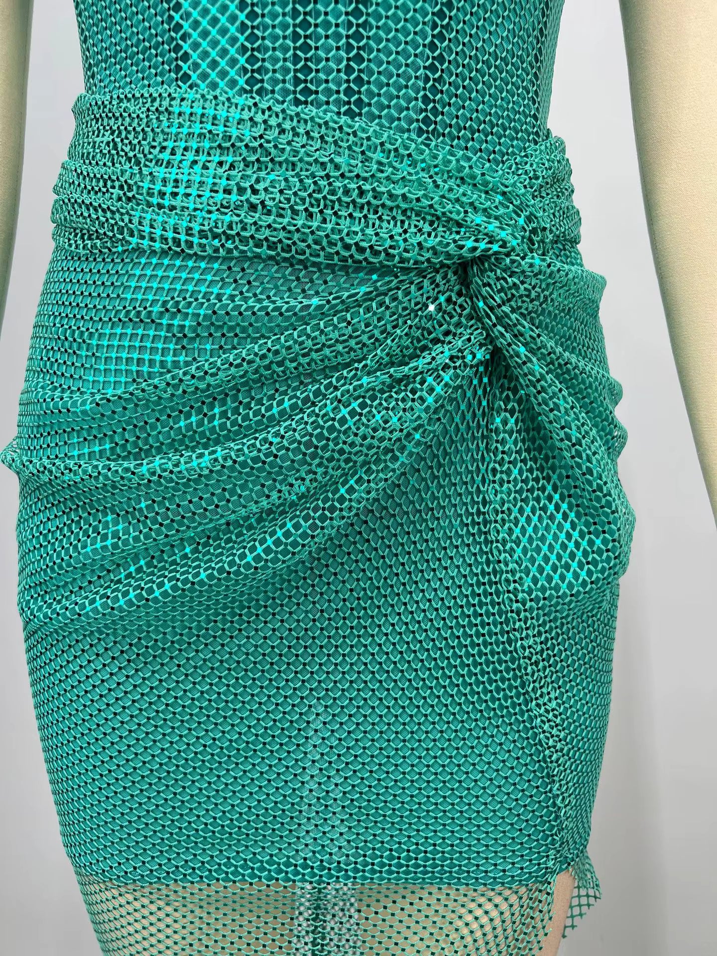 Teal mesh dress on a mannequin against a neutral background