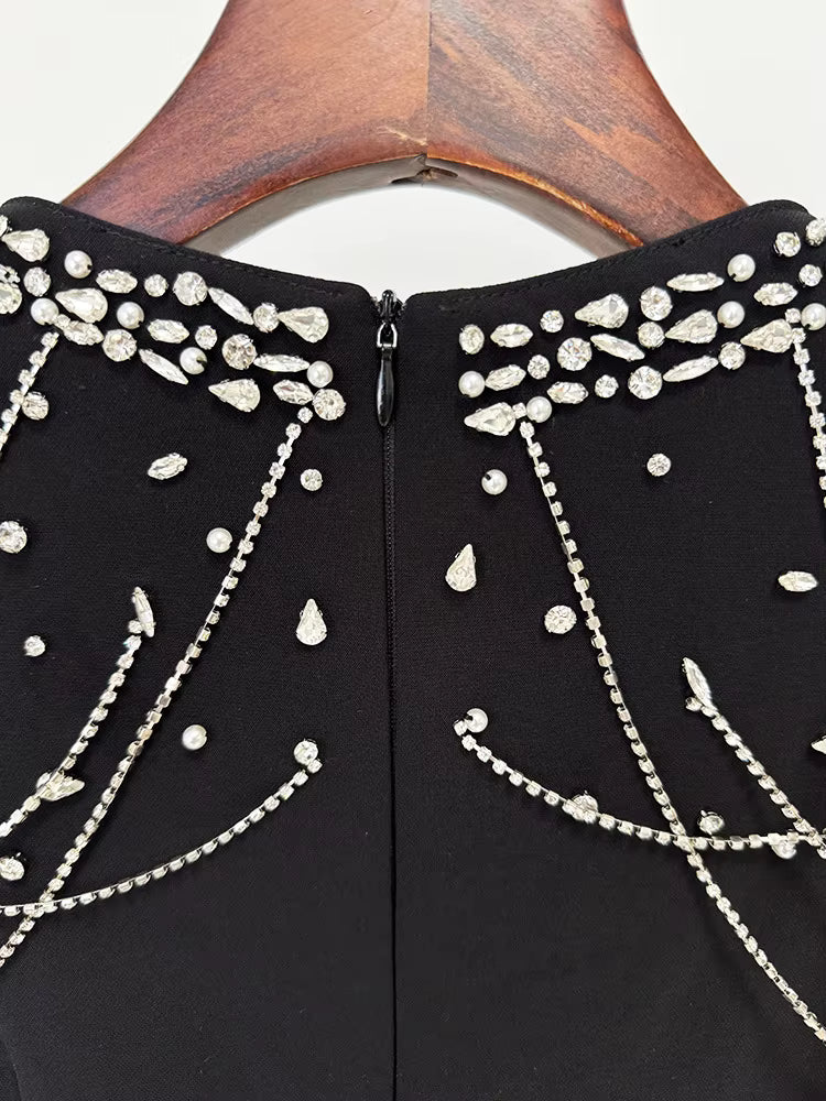 Black garment with silver bead detailing on a wooden hanger