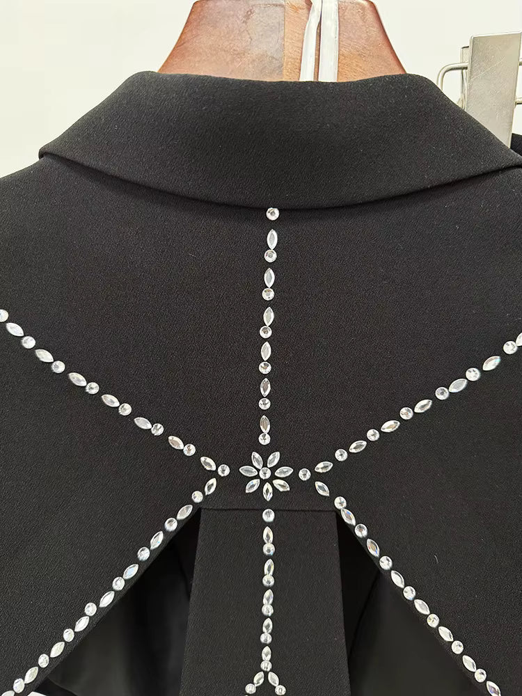 Black garment with decorative silver embellishments on a mannequin.