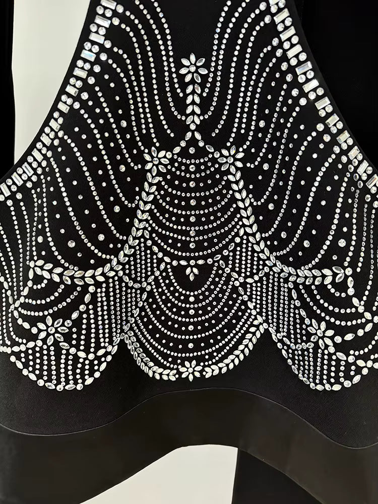 Black top with intricate white beadwork on a plain background