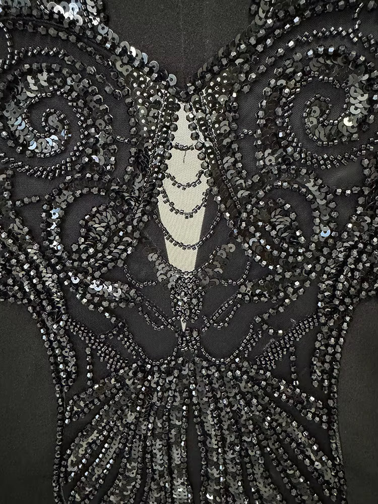 Close-up of a black evening gown with intricate silver beadwork on a mannequin.