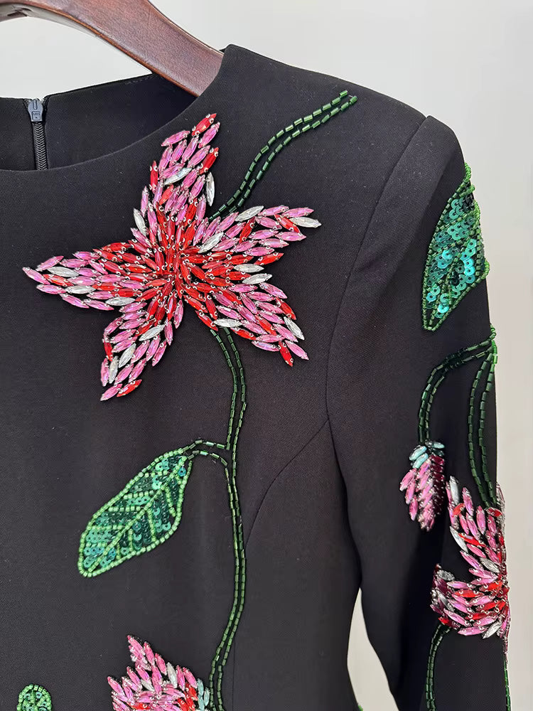 Black dress with pink and green floral embroidery on a white background