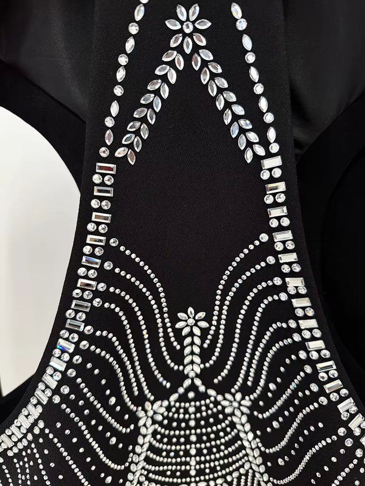 Black garment with intricate white beadwork on a plain background