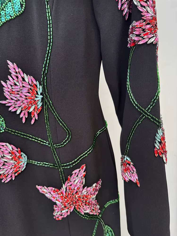 Black garment with colorful floral embroidery on a plain background