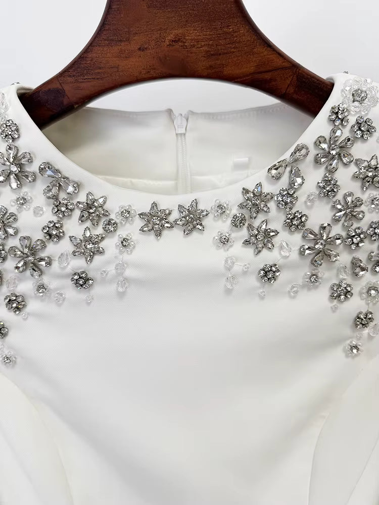 White dress with silver floral embellishments on a wooden hanger