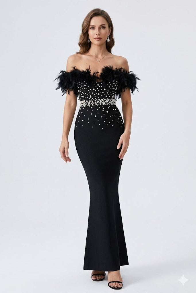 Woman wearing a black off-shoulder gown with feather details and silver embellishments on a white background
