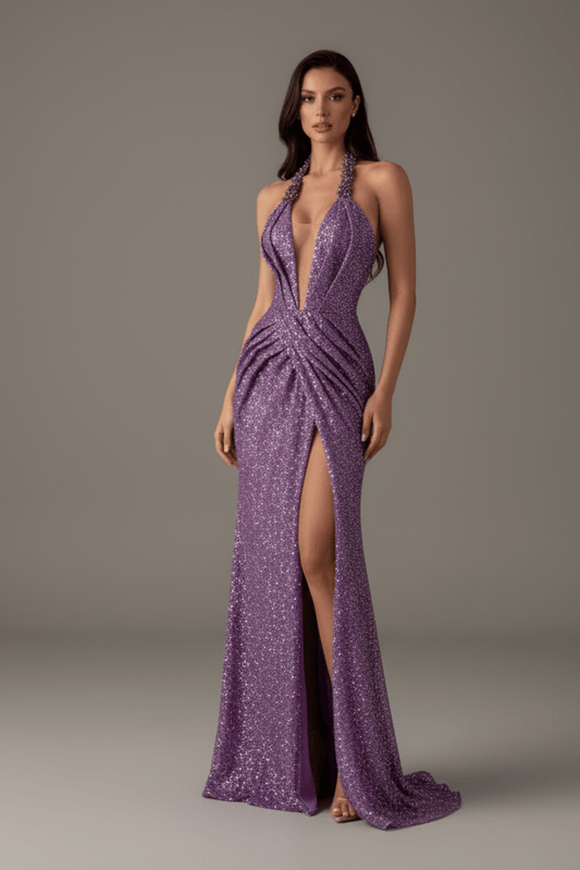 Celina Violet Sequin Halter Backless Prom Gown by Shine | heath gown from Luxe Lane | SKU:  | Barcode:  | Options: Purple XS | Woman wearing a purple evening gown with a high slit on a gray background