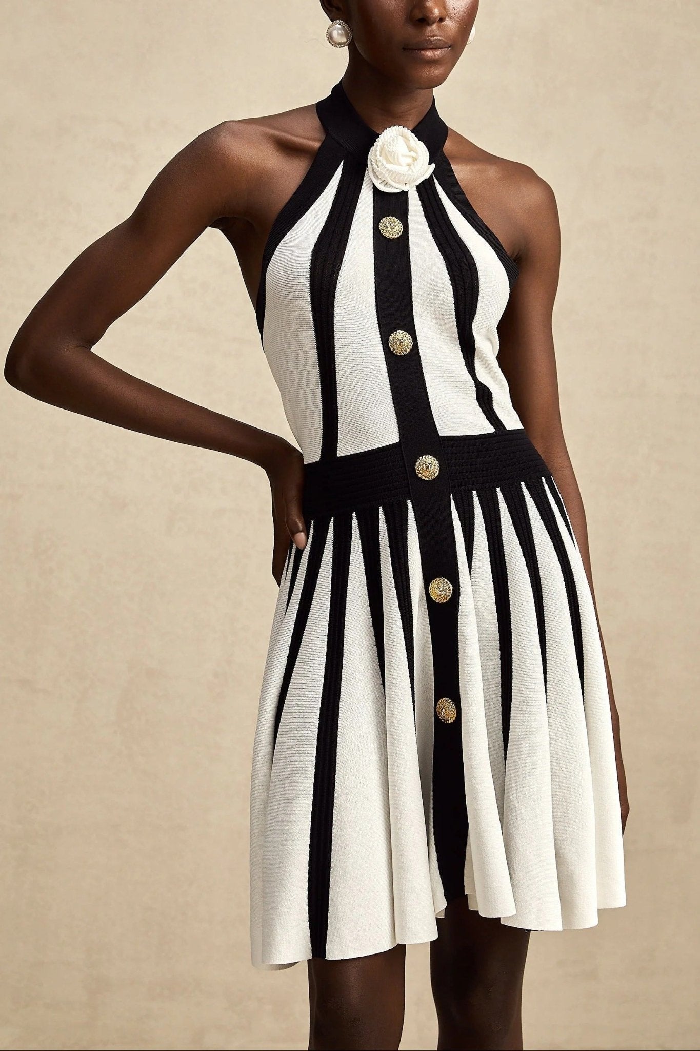 Contrast Halter Neck Pleated Mini Dress by Luxe Lane | from Luxe Lane | SKU: -1 | Barcode:  | Options: Black S(6) | Woman wearing a black and white striped dress with button details on a beige background