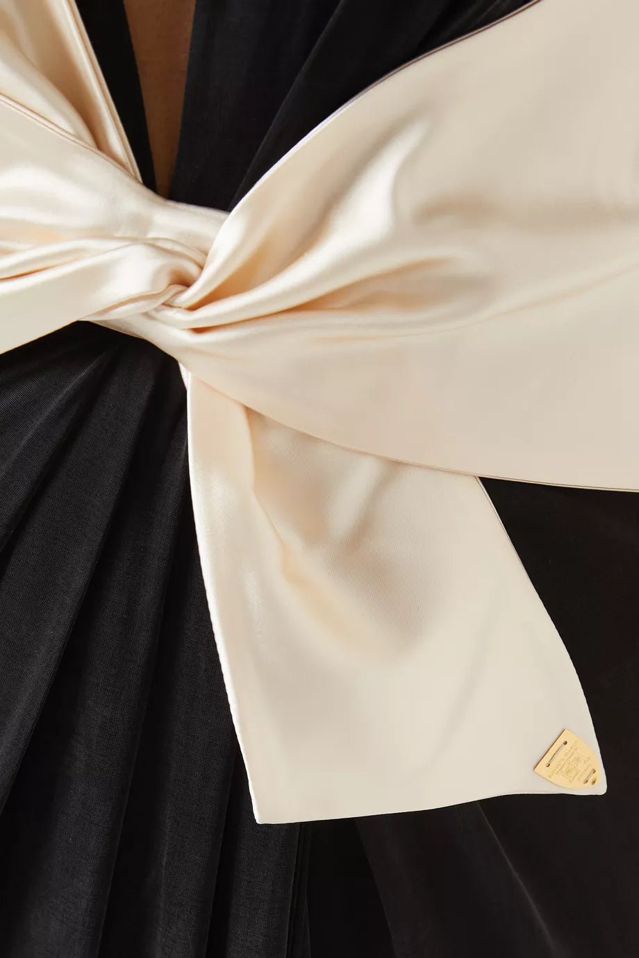 V - Neck Pearl Bow Asymmetrical Maxi Evening Dress by Luxe Lane | Dresses from Luxe Lane | SKU: 1688169-1 | Barcode:  | Options: Black S(6) | Close - up of a large bow made of black and beige fabric with a brand logo.