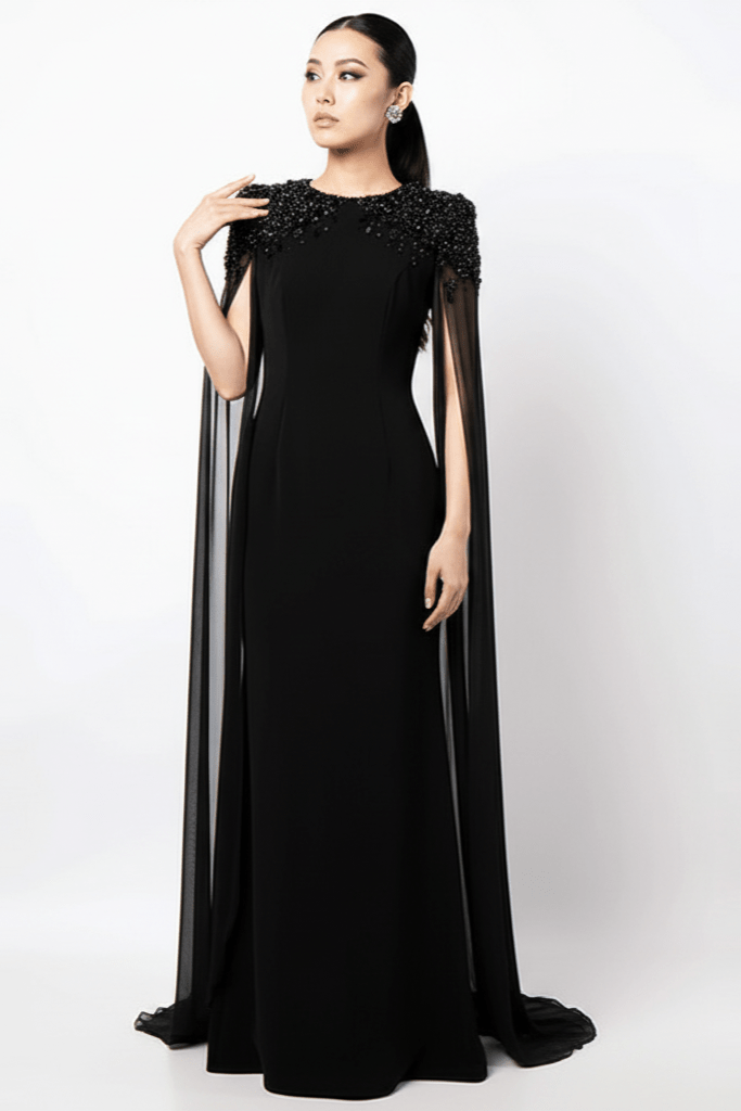 Valencia Beaded Cape Sleeve Evening Gown by none | a - line gown from Luxe Lane | SKU:  | Barcode:  | Options: White S(6) | Woman wearing a black evening gown with sheer sleeves on a white background